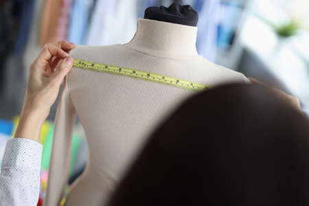 Fashion designer stylist takes measurements of clothes on mannequinの写真素材