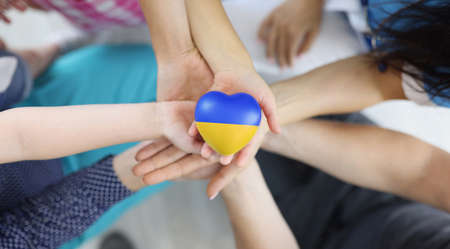 Group of people holding hearts with flag of Ukraine in their hands closeup top view