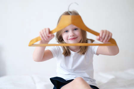 Little girl holding wooden clothes hanger in handsの写真素材