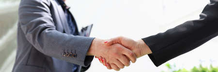 Business man and woman in suits shaking hands closeupの写真素材
