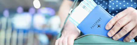 Man putting passport with plane tickets in laptop bag closeupの写真素材