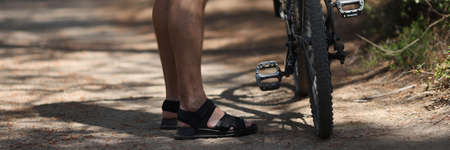 Man standing near mountain bike on path in forest closeupの写真素材