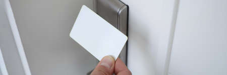 Male hand putting key card to lock on door closeupの写真素材