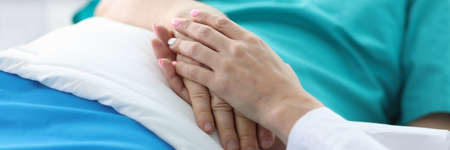 Doctors hands hold hands patient lying in ward