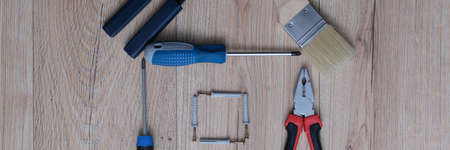House figure assembled from construction tools on wooden background