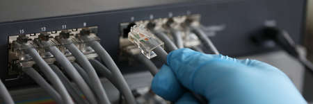 Person working in network server room with fiber optic hub for digital communications and internetの写真素材