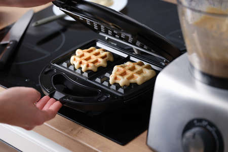 Cooking waffles in waffle iron at home closeupの写真素材