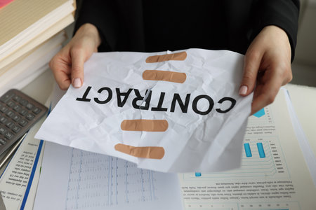 Torn sheet of paper with word contract glued with adhesive tapeの写真素材
