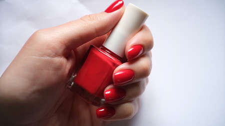 Female nails holds bottle of bright red nail polishの写真素材