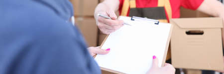 Courier holds parcel, woman signs document
