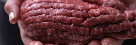 Female hands hold red minced meat, close-up