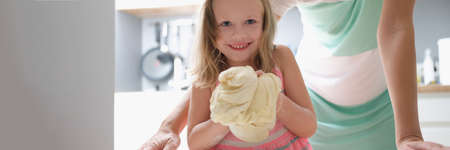 Little girl shows the dough and smilesの写真素材