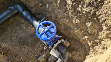 Blue faucet to control sewerage system in ground.