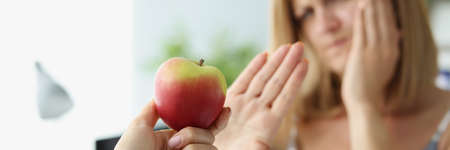 Person give apple to friend and woman refuse to eat because of tooth painの写真素材