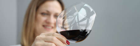 Young pretty woman holding glass of exquisite red wine and slants liquid inside