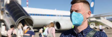 Man wearing mask and standing near airplane
