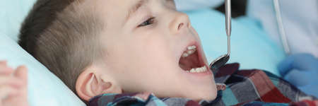 Pediatrician check kids health condition using special tool for mouth