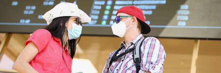 Couple waiting for flight holding tickets and wearing face masks