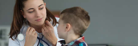 Little boy sitting on doctor appointment, qualified pediatrician wear stethoscope