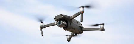 Modern drone device with remote controller flying and filming in airの写真素材