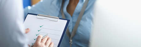 Brunette woman answer to survey questions to coworker standing with paperの写真素材