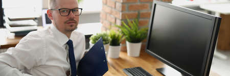 Business office worker sitting on workplace with clipboard