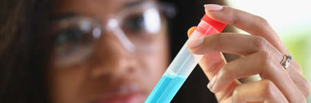 Dark-skinned female laboratory assistant holding a test tube