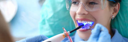 Dentist works with dental polymerization lamp in oral cavityの写真素材