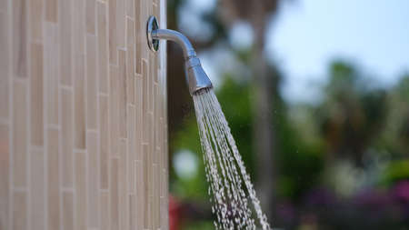 Water flowing from shower near pool in hotel closeup