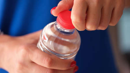 Female hands opening plastic water bottle closeupの写真素材
