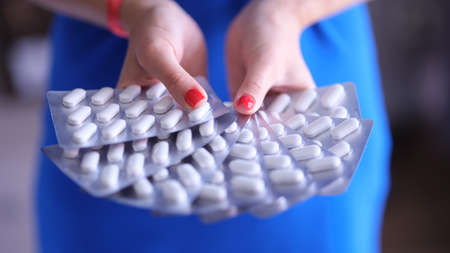 Female hands holding lot of blisters with pills closeup