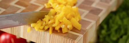 Professional chef put in glass bowl cutted pieces of yellow pepper add to fresh tomatoes