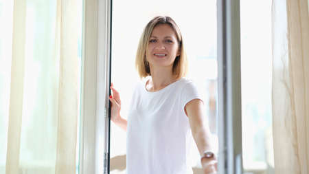 Beautiful smiling woman opens a glass door