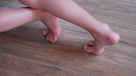Children feet slide on wooden laminate at home