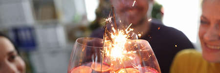 Friends celebrating at party with cocktails and sparklers