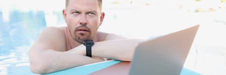 Annoyed man working on a laptop from the pool