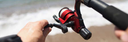 Hands hold a fishing rod against the background of sea coastの写真素材