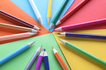 Multi-colored pencils on colored paper on tableの写真素材
