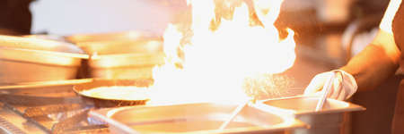Chef cooking something delicious on stove, burning flame from dishの写真素材