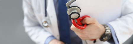 Doctor holding medical equipment red stethoscope and patient medical historyの写真素材