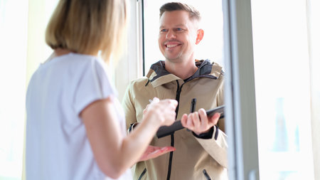 Woman signs on a tablet for parcel from courier at homeの写真素材