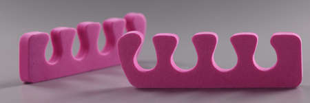 Pink toe divider on gray background. Pedicure accessory