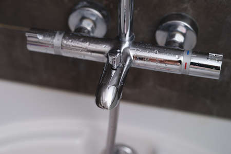 Chrome faucets on white ceramic bathtub in bathroom