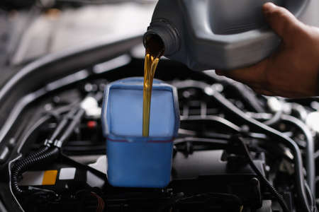 Pour gear oil into car through watering canの写真素材