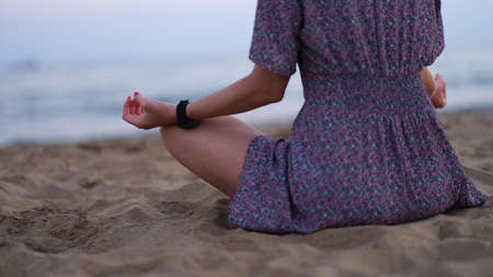 Cropped shot of unrecognizable young woman meditating on beachの写真素材