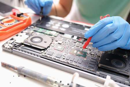Technician measures the voltage on motherboard of computer electronic digital multimeter