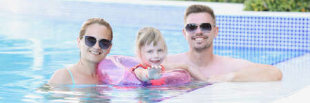 Young family with child in circle in pool on vacationの写真素材