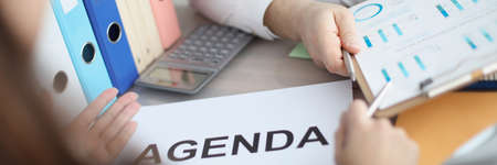 Man and woman sitting at table with documents with agenda closeup
