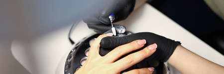 Woman master making manicure to client using special machine in beauty salon closeup