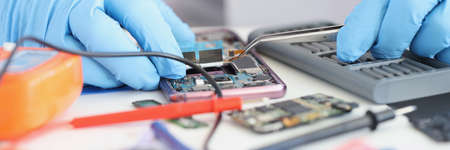 Master repairman inserting microchip into mobile phone closeupの写真素材